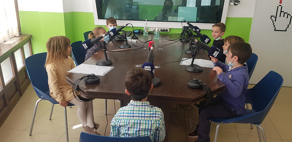 Alumnat al voktant d'una taula amb papers de guions i micròfons